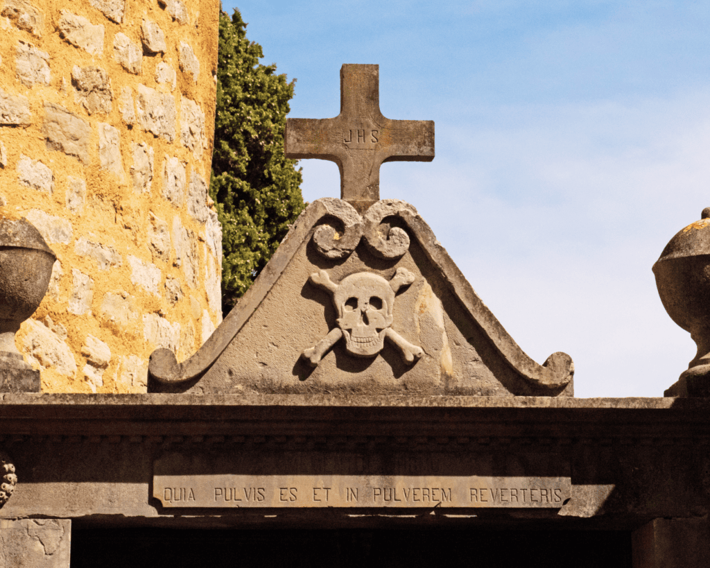 The entrance to the cemetery at rennes-le-château showing a memento mori and a cross